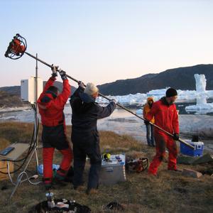 Boring ned gennem den 3 m tykke, permafrosne køkken-mødding Qajaa på sydsiden af Ilulissat Isfjord. Der skal indsamles prøver til analyse, og installeres temperaturfølere ned gennem hullet, for at kunne vurdere om møddingen vil tø op som følge af 