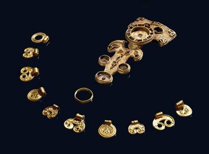 Det 1500 år gamle smykkesæt af guld består af et dragtspænde - en såkaldt rygknapfibula - en fingerring samt 10 hængesmykker. 