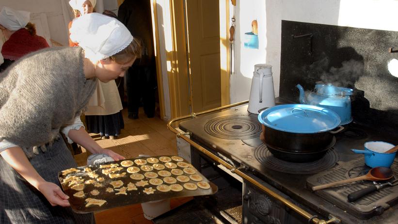 Kokkepige sætter plade med småkager i ovnen